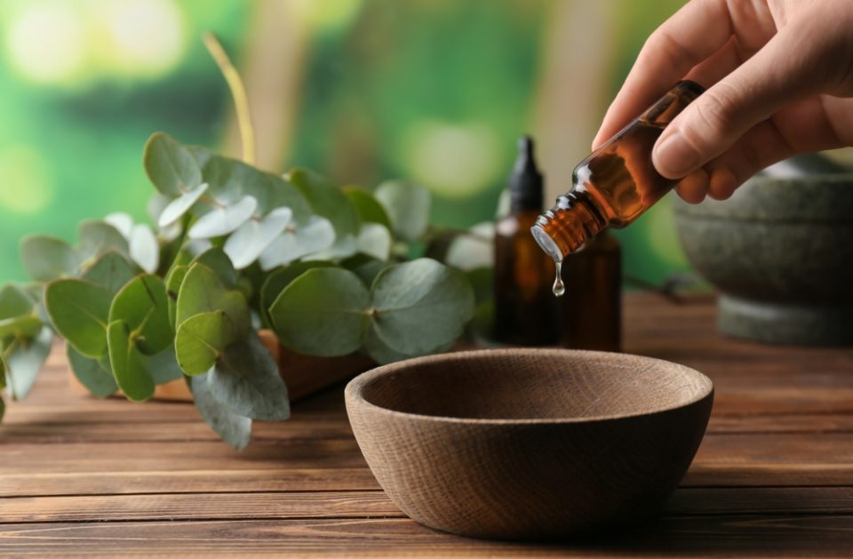 Woman,Pouring,Eucalyptus,Essential,Oil,Into,Bowl,On,Wooden,Table